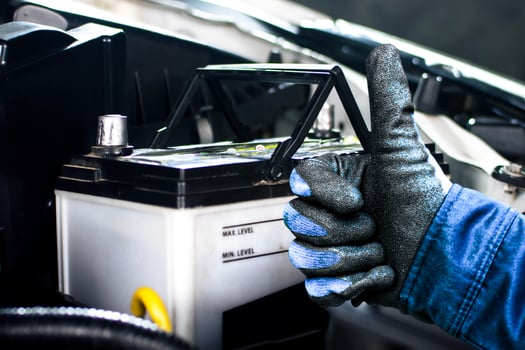 Auto mechanic thumbs up with confidence next to car battery , battery replace in car repair garage , Car maintenance concept photo