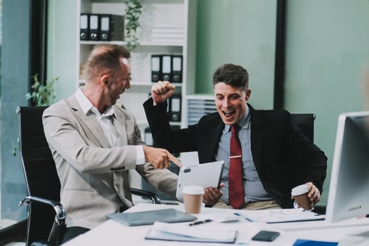 Two happy colleagues with laptop and documents in office photo