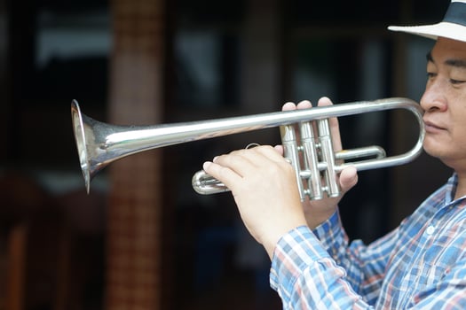 Close up Asian man is playing trumpet. Concept, love music, hobby, recreation activity. Relax time. Lifestyle. Music can develop mental health. Mouthpiece musical instrument. Rehearsal music. photo
