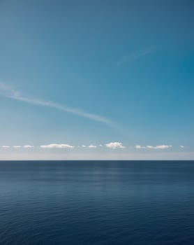 A blue sky and a white cloud over the ocean photo