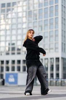 Young dancer performing urban dance in front of modern city buildings photo