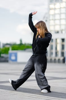 Young dancer performing dynamic movement outside modern buildings photo