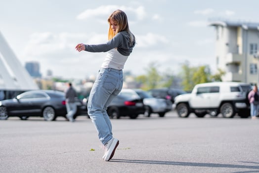Young woman dancing joyfully in a parking lot on a sunny day photo