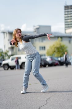 Young woman dancing in urban setting during daytime at a parking area photo