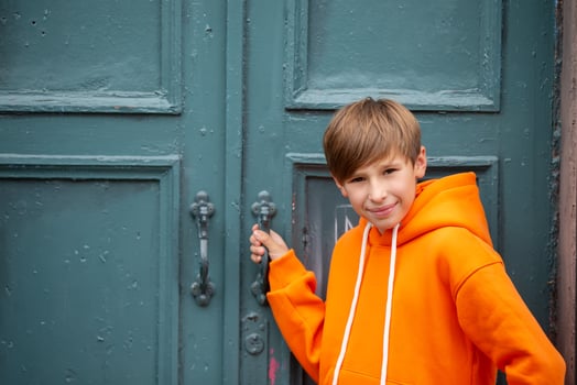 A teenage boy opens a closed door and looks at the camera. photo
