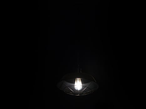 A light bulb is hanging from a black ceiling photo