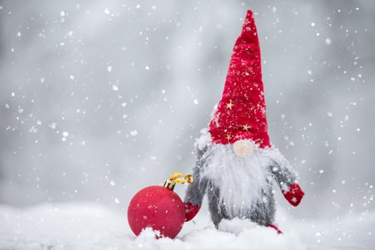 A Christmas card. Cute dwarf in a red hat on a winter background. photo