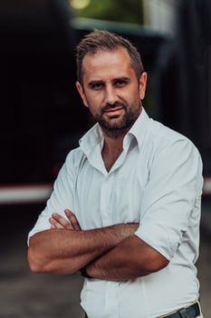 A successful businessman in a white shirt with crossed arms posing outdoors photo