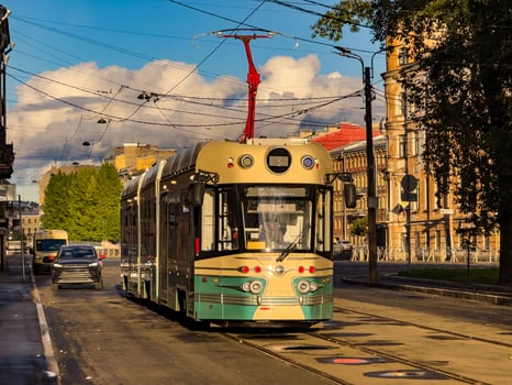 A vintage-inspired tram travels down a quiet street in Saint Petersburg, illuminated by the warm afternoon sunlight. The tram retro design harmonizes with the historic architecture of the city photo