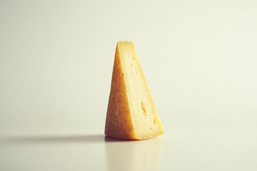 A Wedge of Aged Hard Cheese with Holes and Rough Surface photo