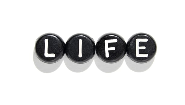 Life concept with black stones and white letters isolated on white background. photo