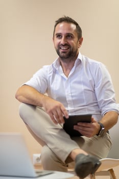 A confident businessman sitting and using laptop with a determined expression, while a beige background enhances the professional atmosphere, showcasing his productivity and expertise. photo