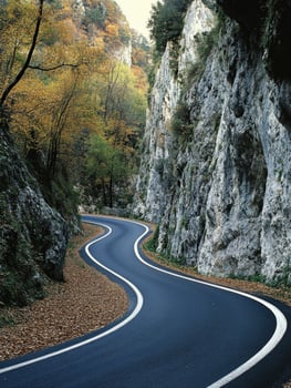 Winding road through autumn foliage in a rocky landscape photo