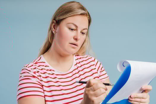 Young plus size woman making notes posing in studio over blue background photo