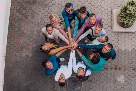 Top view photo of a group of business people and colleagues standing together holding hands, looking towards the camera, symbolizing unity and teamwork.