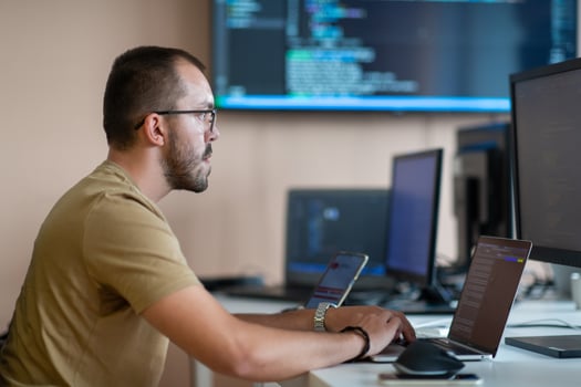 A programmer diligently testing smartphone applications while sitting in their office. photo