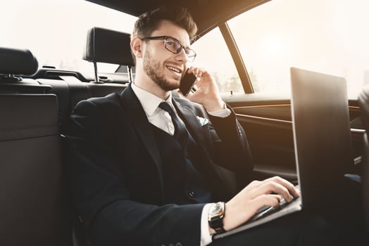 Always In Touch. Confident chief executive in suit using personal computer and making phone call in taxi, copy space, flare light photo