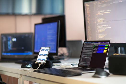 Computer screens running programming code in empty software developing agency office and computers parsing data algorithms in background. Neural network servers cloud computing in data room. photo