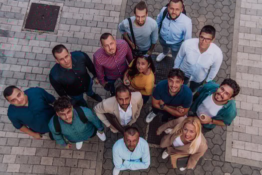 A top view photo of group of businessmen and colleagues standing together, looking towards the camera, symbolizing unity and teamwork.