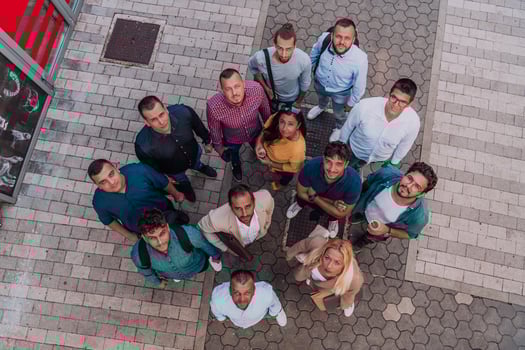 A top view photo of group of businessmen and colleagues standing together, looking towards the camera, symbolizing unity and teamwork.
