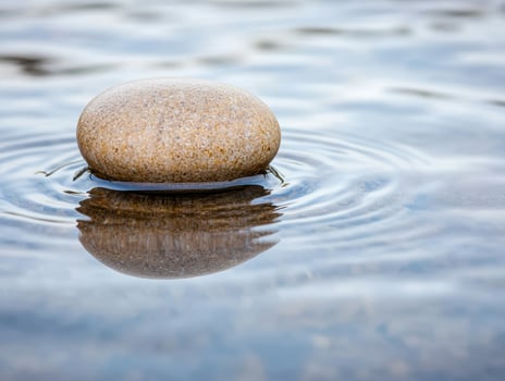 Smooth stone floating on calm water photo