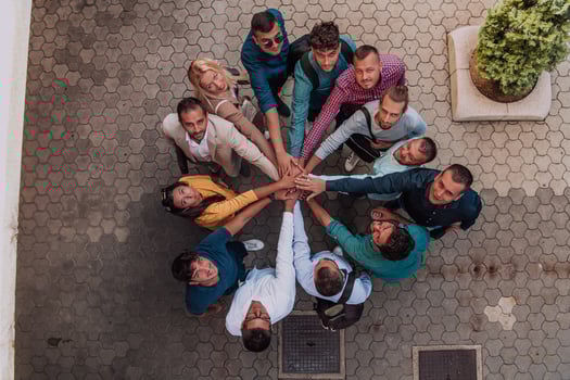 Top view photo of a group of business people and colleagues standing together holding hands, looking towards the camera, symbolizing unity and teamwork.