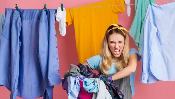 Wicked housewife with dirty laundry, powder and conditioner on pink background photo