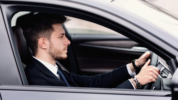 Successful Businessman Concept. Confident young chief executive driving alone in his luxury car, side view photo