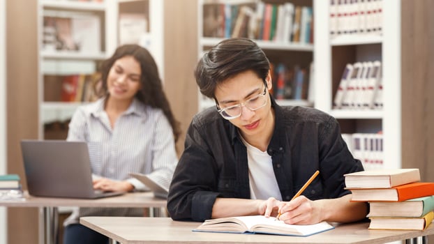 Learning And Education Concept. Korean male student studying in campus library, doing homework, copyspace photo