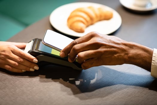 Online Bill Payment Concept. Black man holding smartphone close to electronic payment machine while paying in cafe photo
