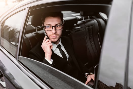 Always Available. Male ceo in suit and glasses talking on smart phone sitting in taxi cab, looking out of window photo