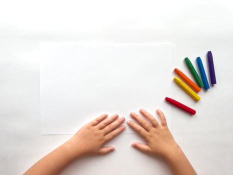 Childs hands preparing to draw with colorful crayons on white paper photo