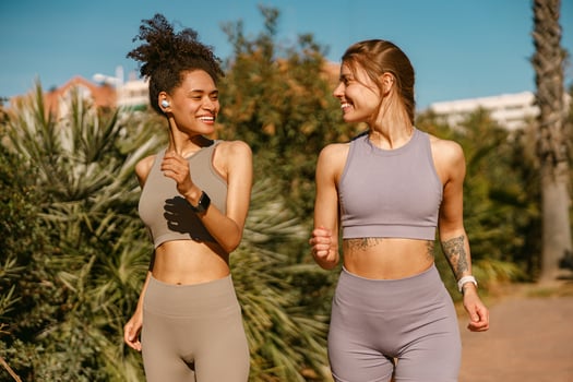 Two active women athlete running side by side along an outdoor track on public park background photo