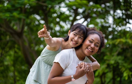 Diversity of LGBTQ lesbian couple is hugging and laughing while enjoy their leisure time outdoor in public park during summer photo