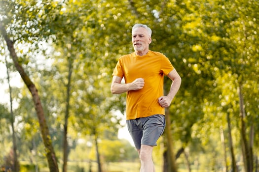 Senior man enjoying running in the park during summertime photo