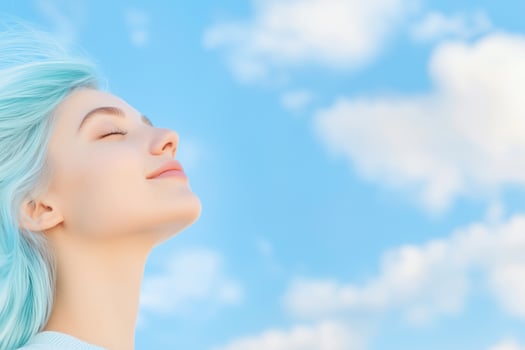 A young woman with bright blue hair embraces the wind under a vibrant blue sky photo
