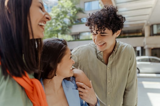 Three young professionals walking and smiling together on city street photo
