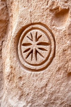 Ancient symbolic patterns carved into stone with worn textures and muted colors representing ancestral wisdom photo