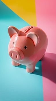 A cute pink piggy bank stands on a vibrant blue and pink background during daytime photo
