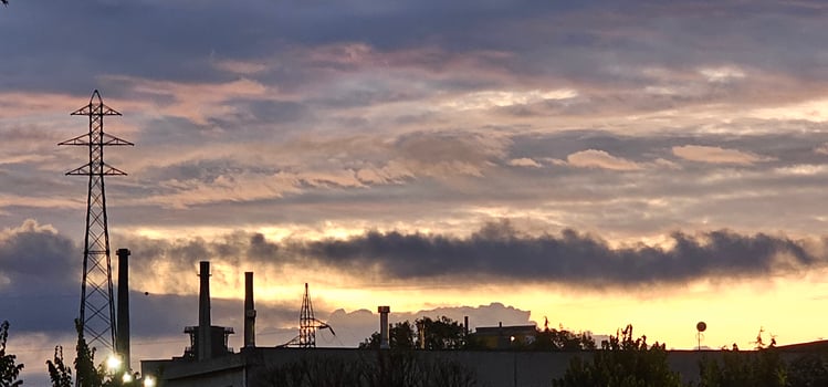 fiery sunset with smog fumes from chimneys at a metalworking industry in Italy photo