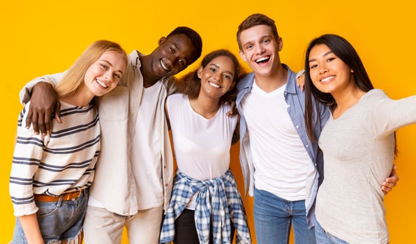Friendly international group of teenagers embracing and taking selfie over yellow background photo