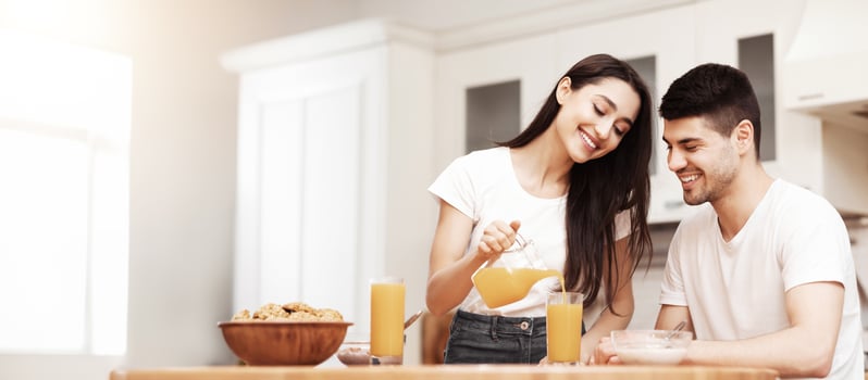 Cute european family having breakfast at home in the morning, smiling girl pouring lemonade in glasses photo