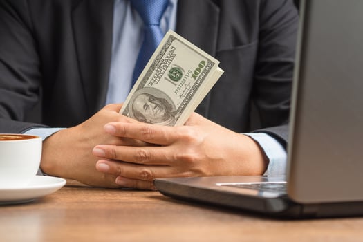Hand of a businessman in a suit holding US dollars banknote while sitting in the office photo