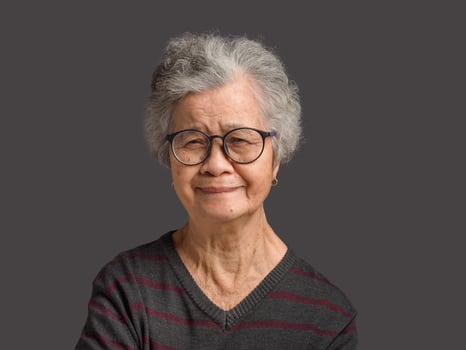 Portrait of a senior woman with short gray hair looking at the camera with a smile while standing on gray background photo