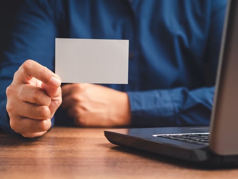 Close-up of hand holding a blank white paper while sitting in the office photo