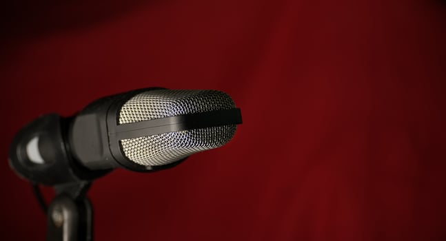 Professional studio microphone with metal mesh grille against dark red background photo