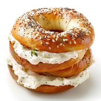 A stack of sesame seed-covered bagels topped with a layer of white cream cheese. photo