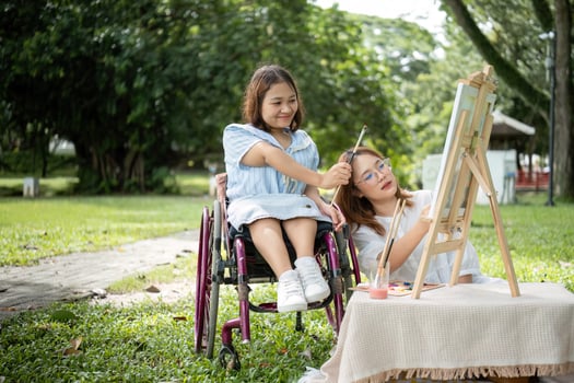 Close Friends, Disabled Young Women Enjoying Outdoor Drawing Session Together in a Park photo