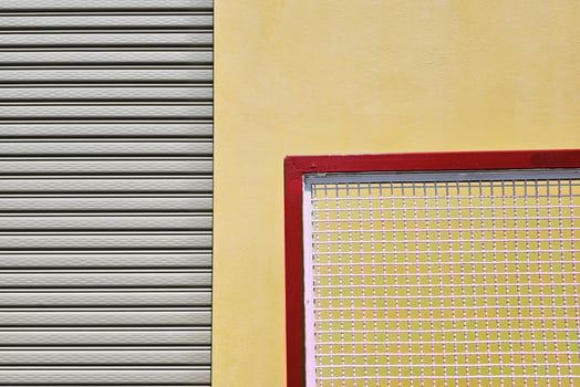 Close up Movable Metal Fence with Foldable Door and Yellow Concrete Wall Background. photo