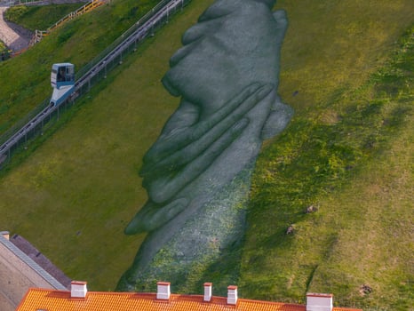 Aerial View of Clasped Hands Artwork on Grassy Hillside in Vilnius photo